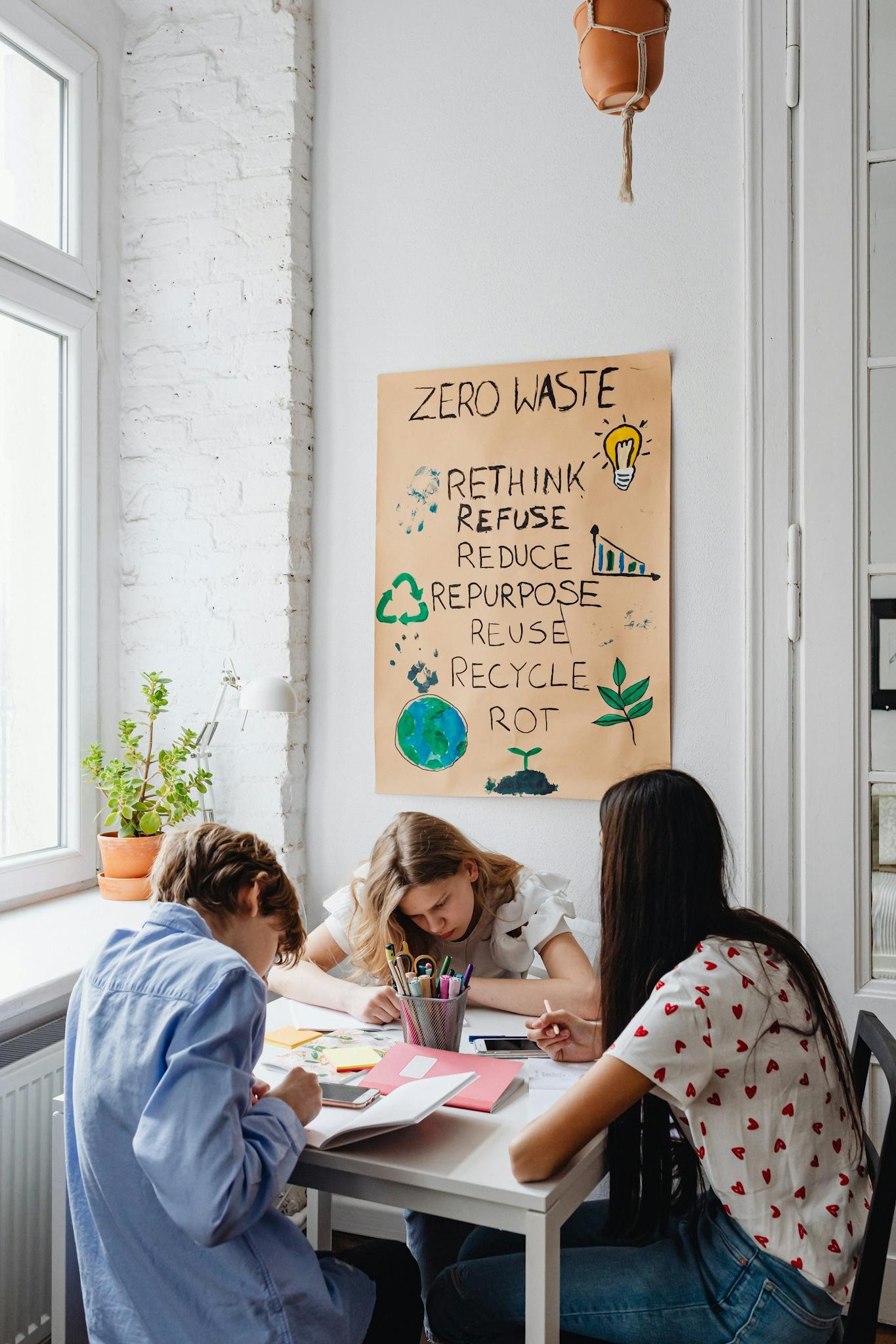Three teenagers working on a zero waste project together at a table, promoting sustainability and environmental awareness.